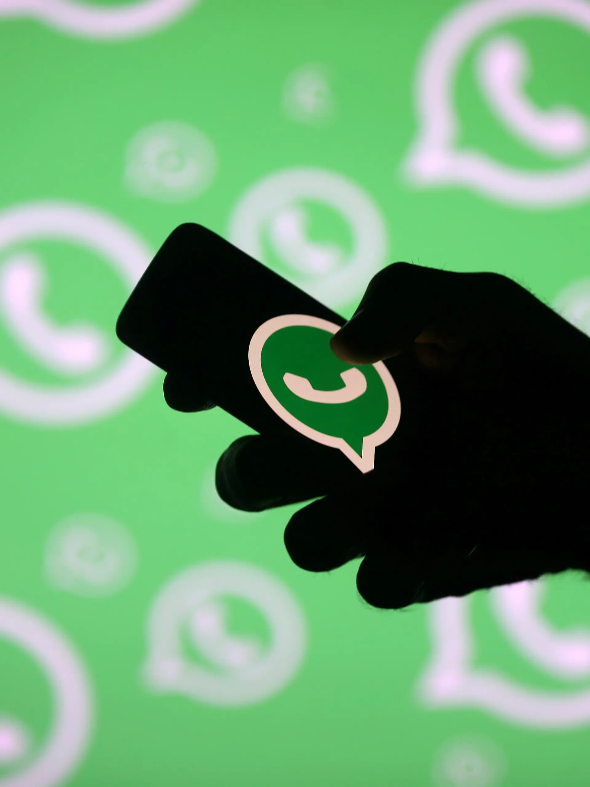 FILE PHOTO: A man poses with a smartphone in front of displayed Whatsapp logo in this illustration picture September 14, 2017. REUTERS/Dado Ruvic/File Photo