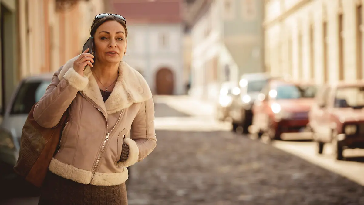 Copy space shot of elegant mature woman standing on the city street and calling a cab to come pick her up.