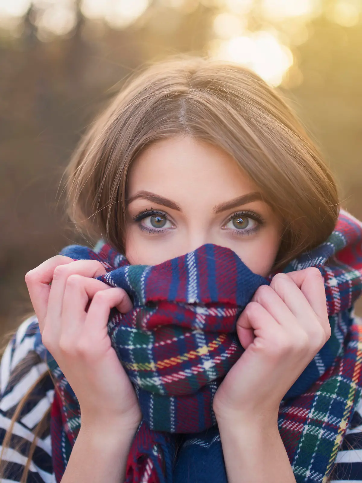 Portrait of a beautiful young woman with face wrapped with a plaid scarf.