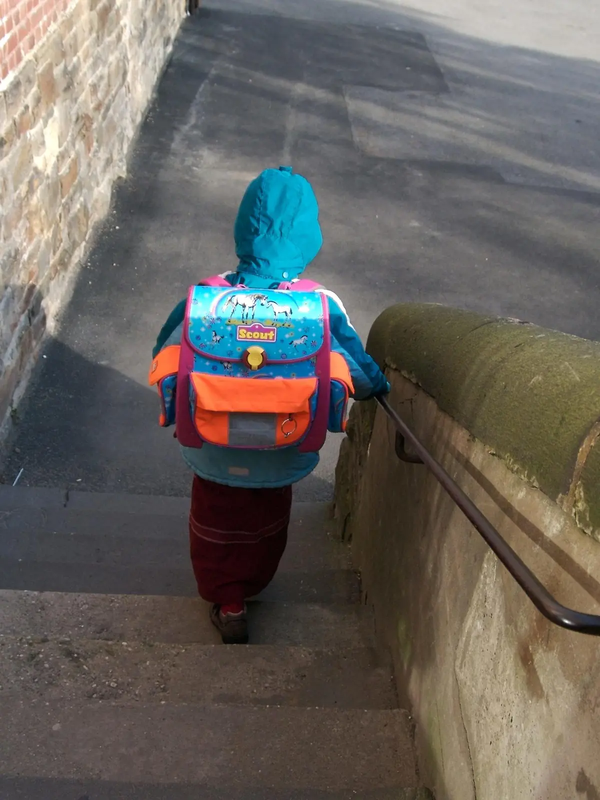 Die Katholische Grundschule 'Passstrasse' ist seit 2005 offene Ganztagsschule. Die Kinder werden auch nach dem Unterricht von Lehrern und pädagogischen Fachkräften betreut. Hier: ein Mädchen mit Schulranzen verlässt die Schule über eine Treppe und macht sich auf den Weg nach Hause. Aachen, Nordrhein-Westfalen, Deutschland, 14.01.2008