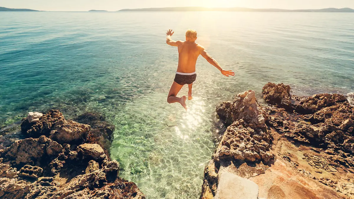 Man jumps in blue sea lagoon water