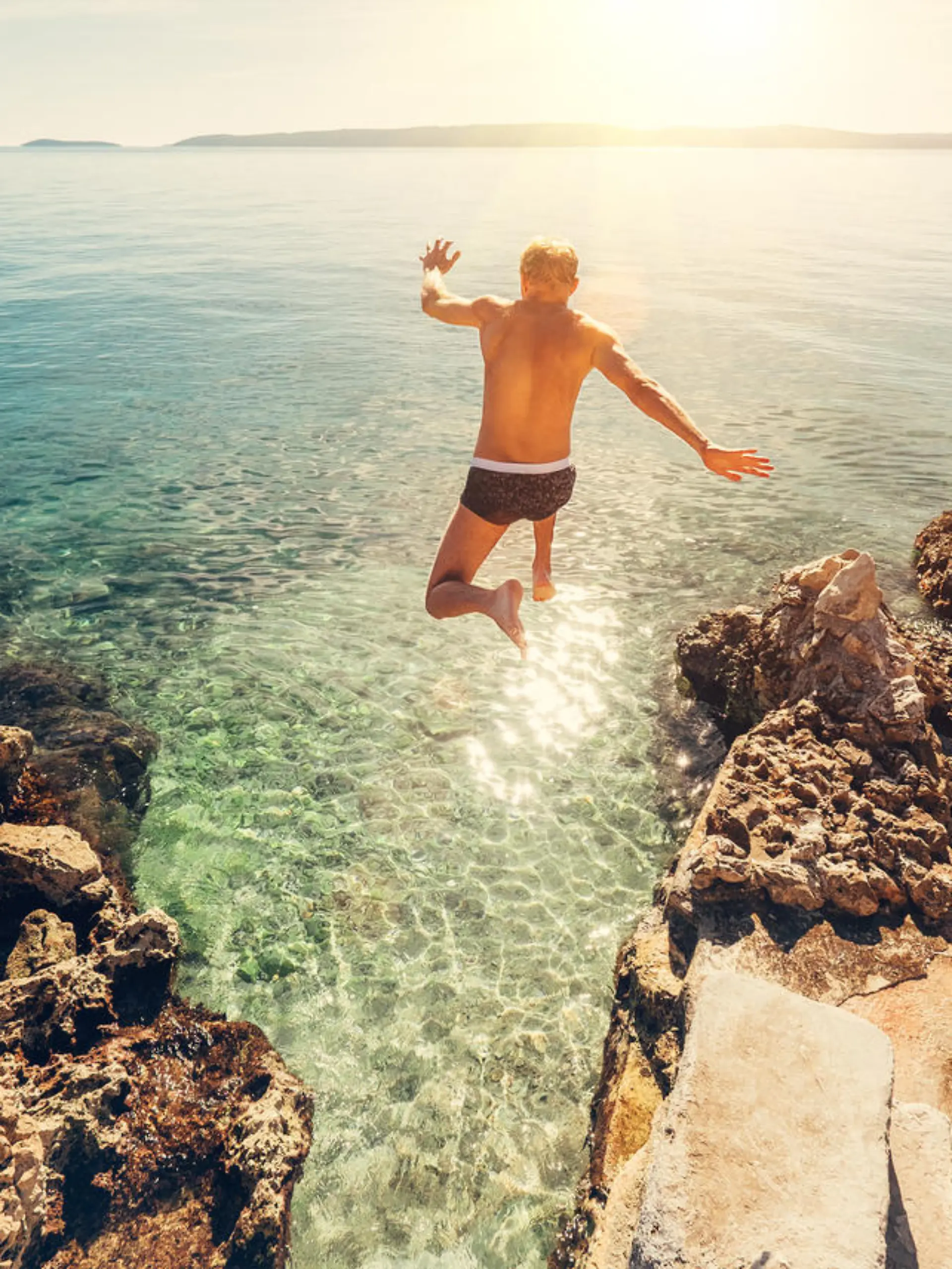 Man jumps in blue sea lagoon water