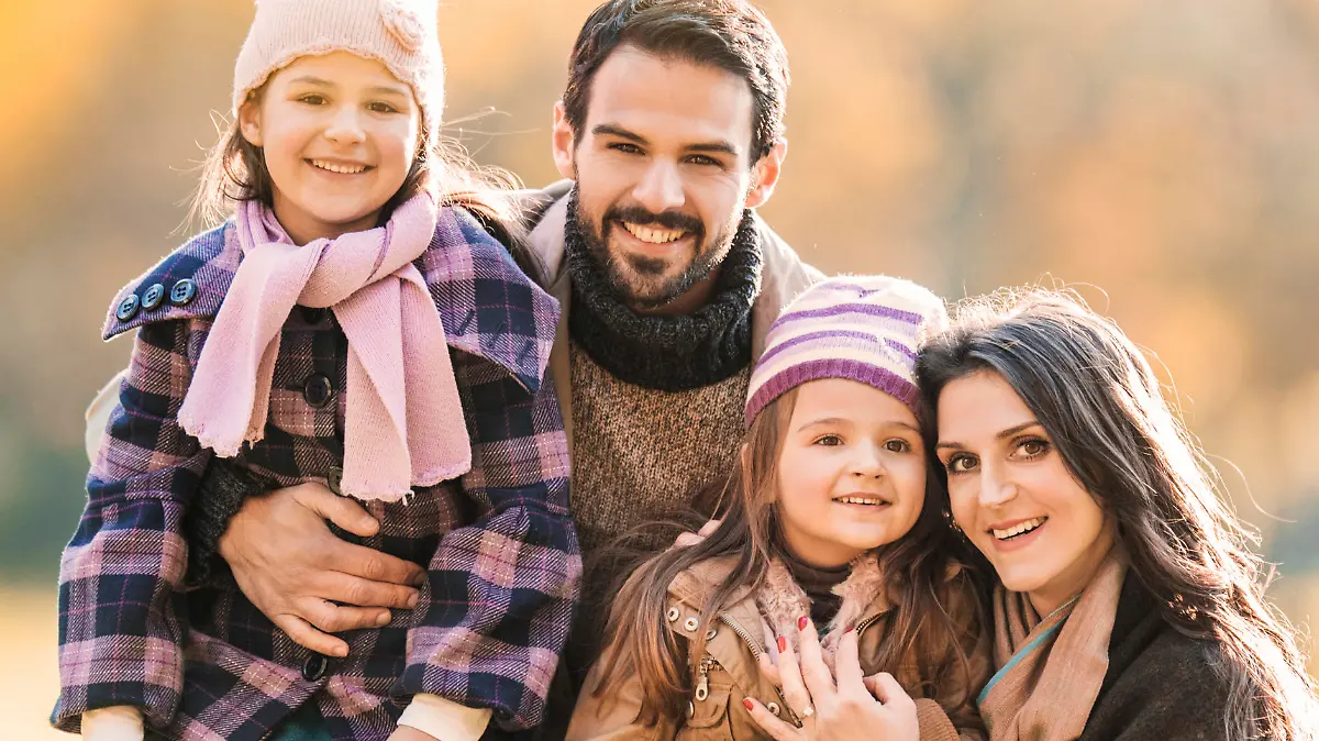 Portrait of happy family enjoying in autumn day and looking at the camera.