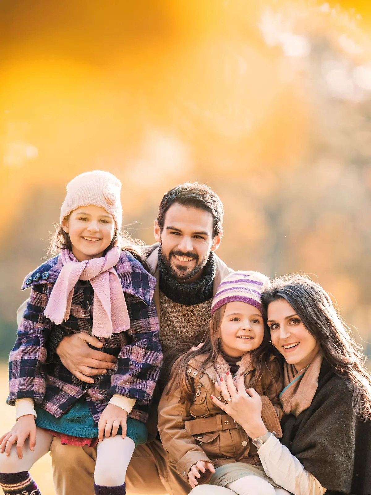 Portrait of happy family enjoying in autumn day and looking at the camera. 