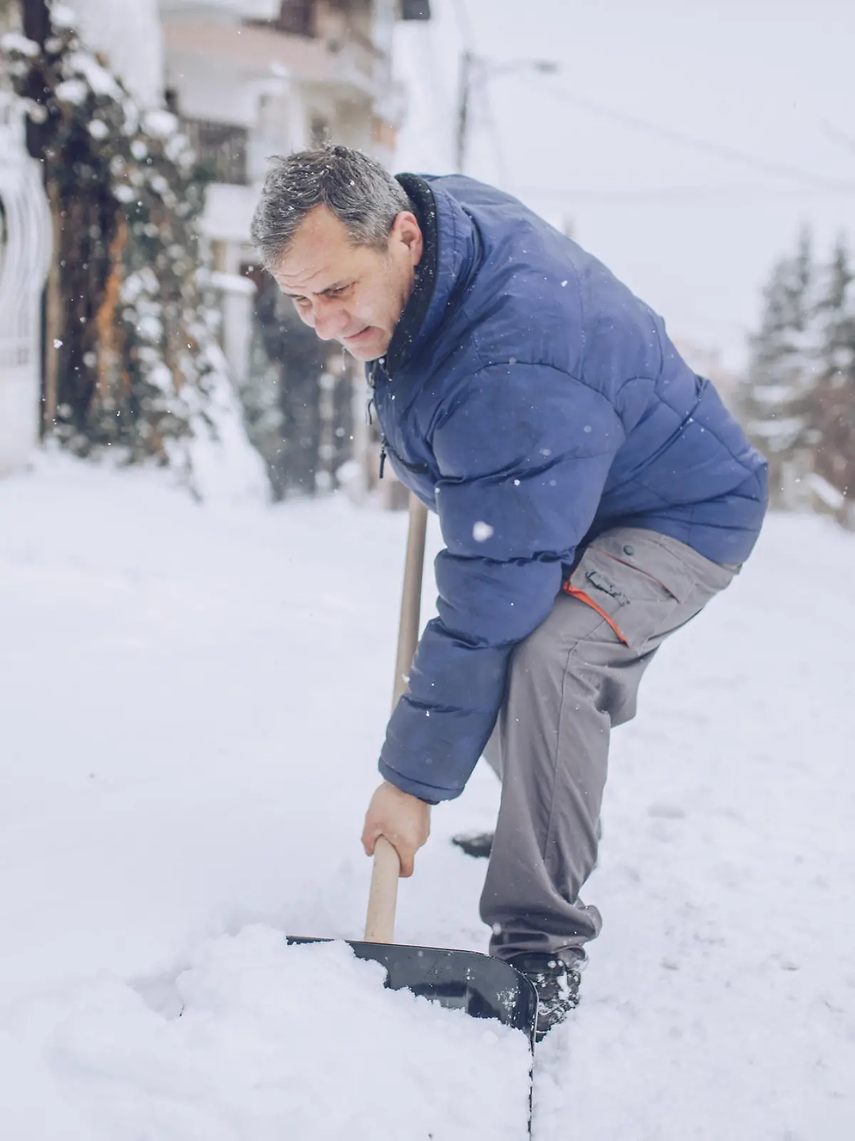 Alter Mann beim Schnee schippen