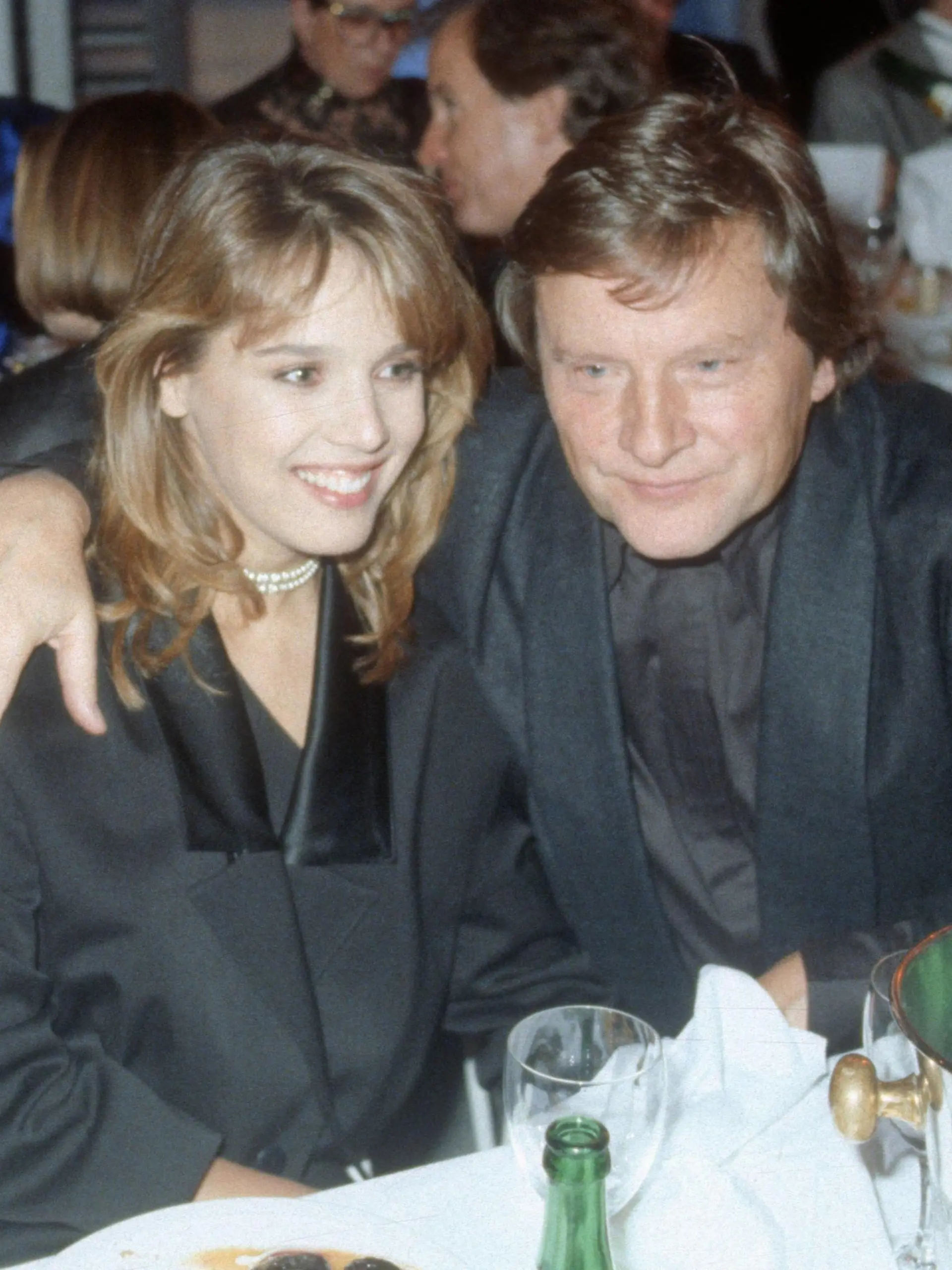  Georg Bossert u. Desiree Nosbusch 11/87 rag seriös quer halb sitzend Geschirr Flasche Sekt umarmend