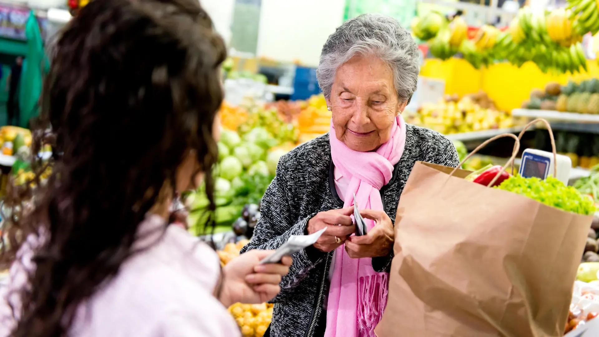 Rentnerin zahlt an der Kasse im Supermarkt