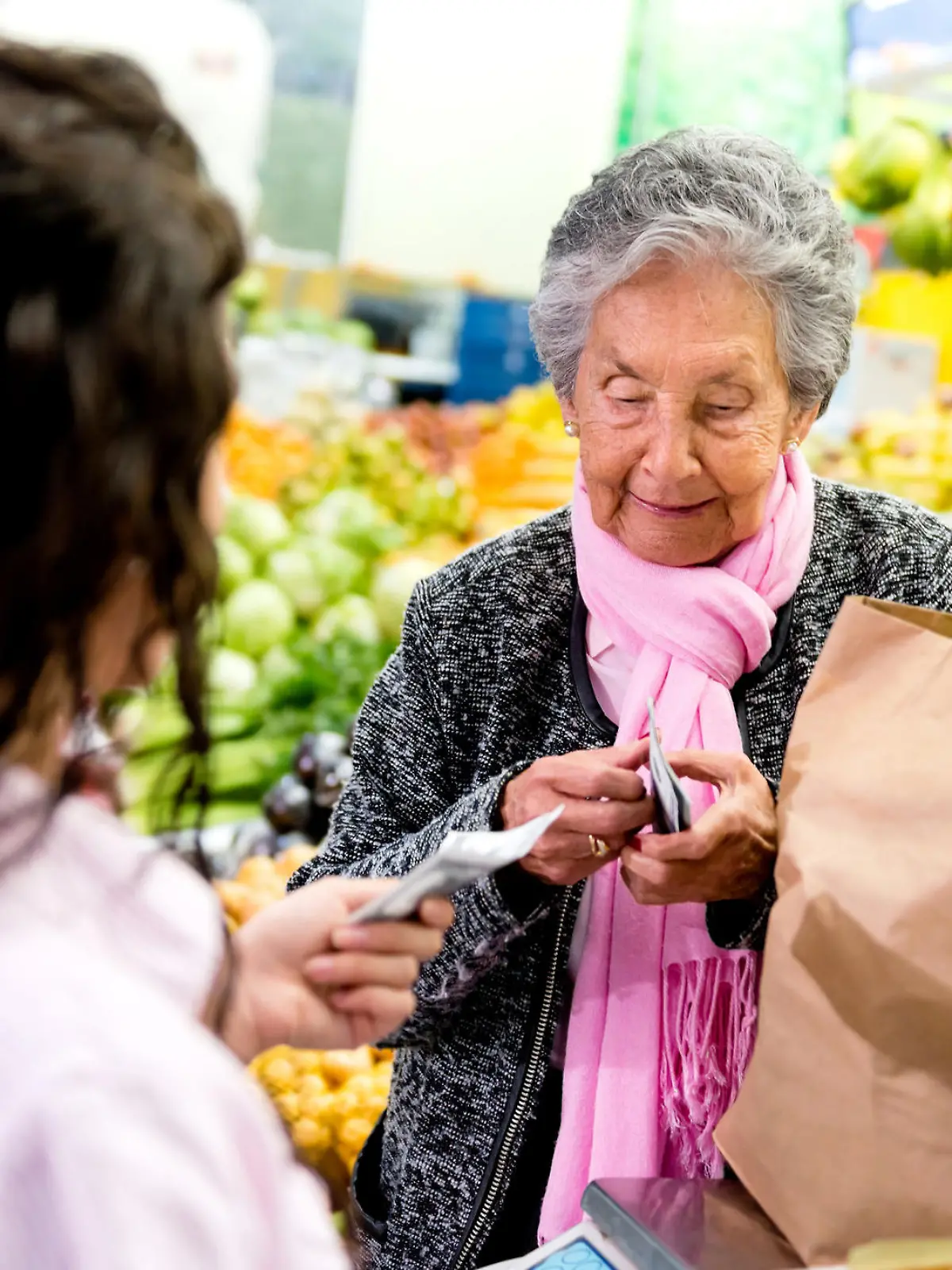 Rentnerin zahlt an der Kasse im Supermarkt