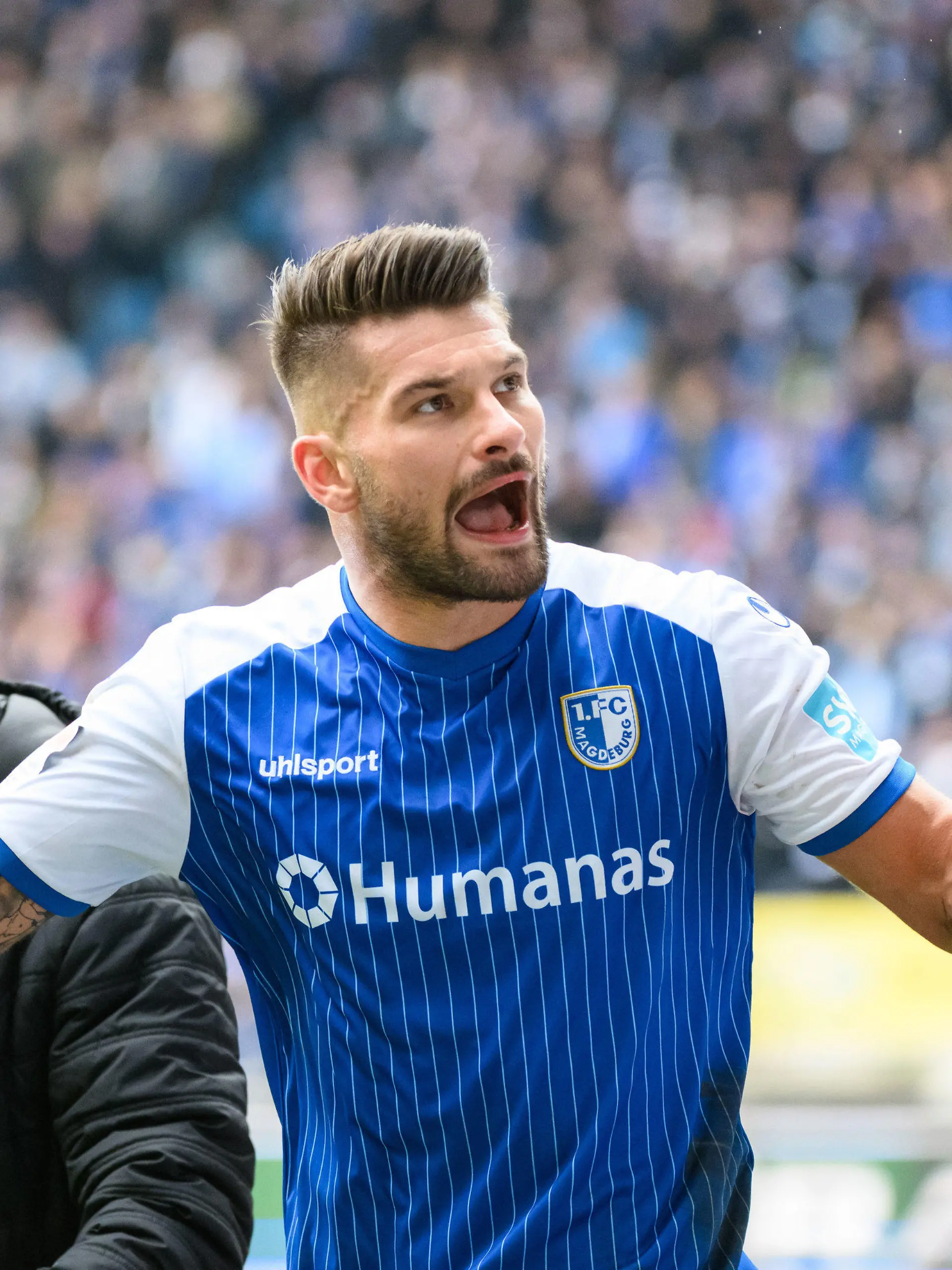 18.02.2023, Sachsen-Anhalt, Magdeburg: Fußball: 2. Bundesliga, 1. FC Magdeburg - FC St. Pauli, 21. Spieltag, MDCC-Arena. Magdeburgs Kai Brünker motiviert die Zuschauer auf der Tribüne. Foto: Christian Modla/dpa - WICHTIGER HINWEIS: Gemäß den Vorgaben der DFL Deutsche Fußball Liga bzw. des DFB Deutscher Fußball-Bund ist es untersagt, in dem Stadion und/oder vom Spiel angefertigte Fotoaufnahmen in Form von Sequenzbildern und/oder videoähnlichen Fotostrecken zu verwerten bzw. verwerten zu lassen. +++ dpa-Bildfunk +++