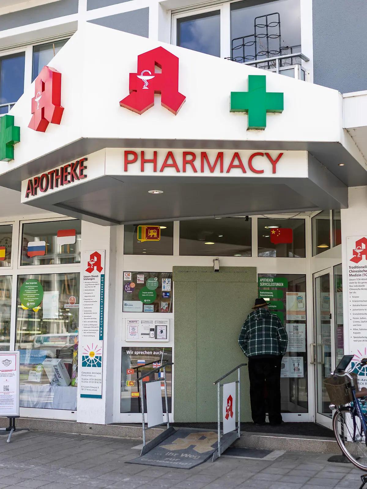 11.03.2023, Baden-Württemberg, Karlsruhe: Ein Mann blickt durch das Fenster der Congress-Apotheke. Am Vorabend hat ein 20-jähriger Täter in der Karlsruher Congress-Apotheke mehrere Geiseln genommen. Kurz nach 21 Uhr haben dann Spezialkräfte der Polizei die Apotheke betreten und den Mann festgenommen. Foto: Philipp von Ditfurth/dpa +++ dpa-Bildfunk +++