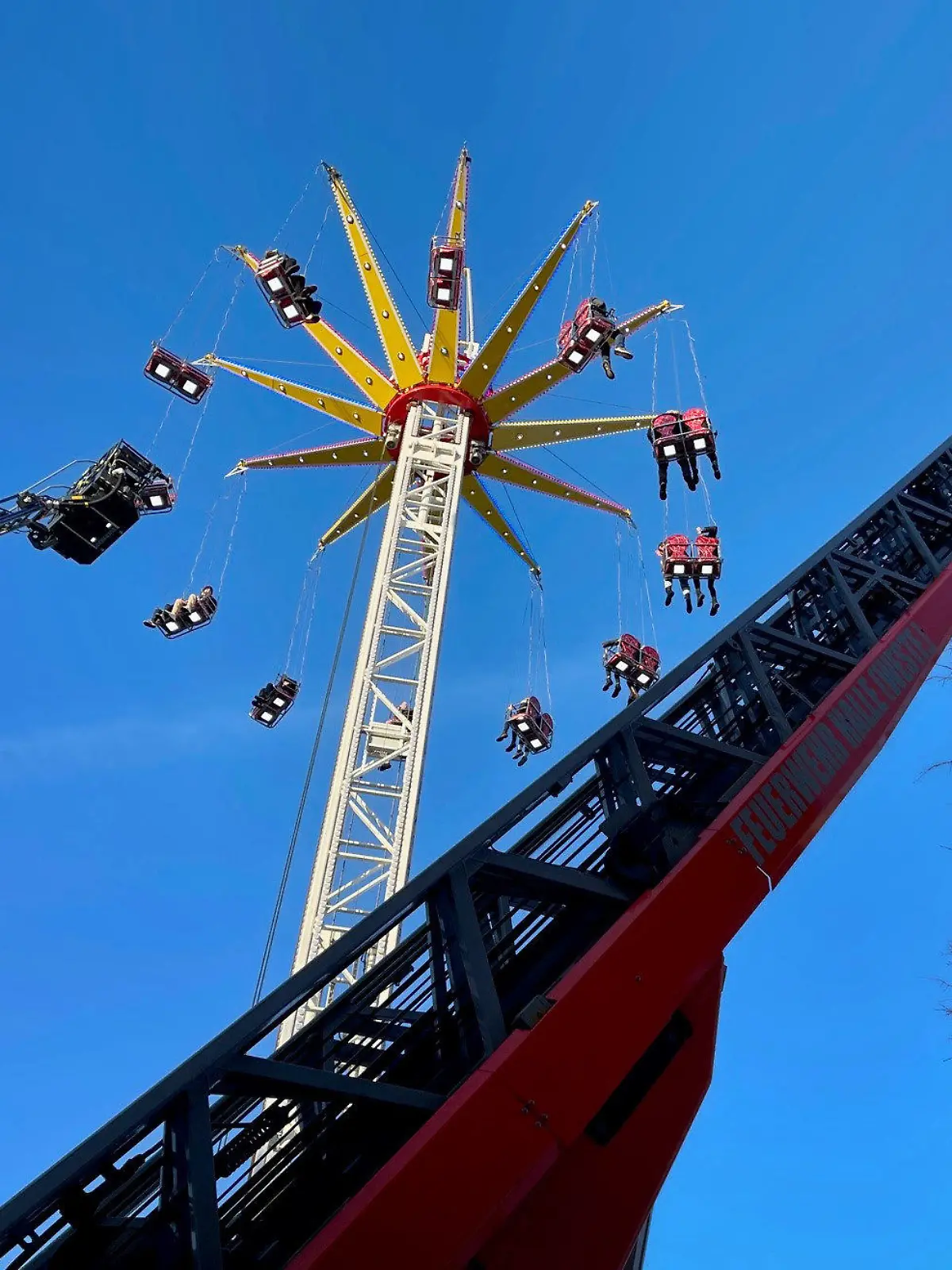 11.03.2023, Nordrhein-Westfalen, Halle: Menschen werden wegen eines Defekts in einem Kettenkarussell auf einer Kirmes in Halle (Westfalen) von der Feuerwehr mit Leiterwagen gerettet. Die letzten Mitfahrer konnten am Samstagnachmittag nach rund 75 Minuten zu Boden befördert werden, sagte ein Polizeisprecher. (Zu dpa «24 Menschen harren in Kettenkarussell aus ») Foto: Christian Müller/Westfalennews/dpa +++ dpa-Bildfunk +++