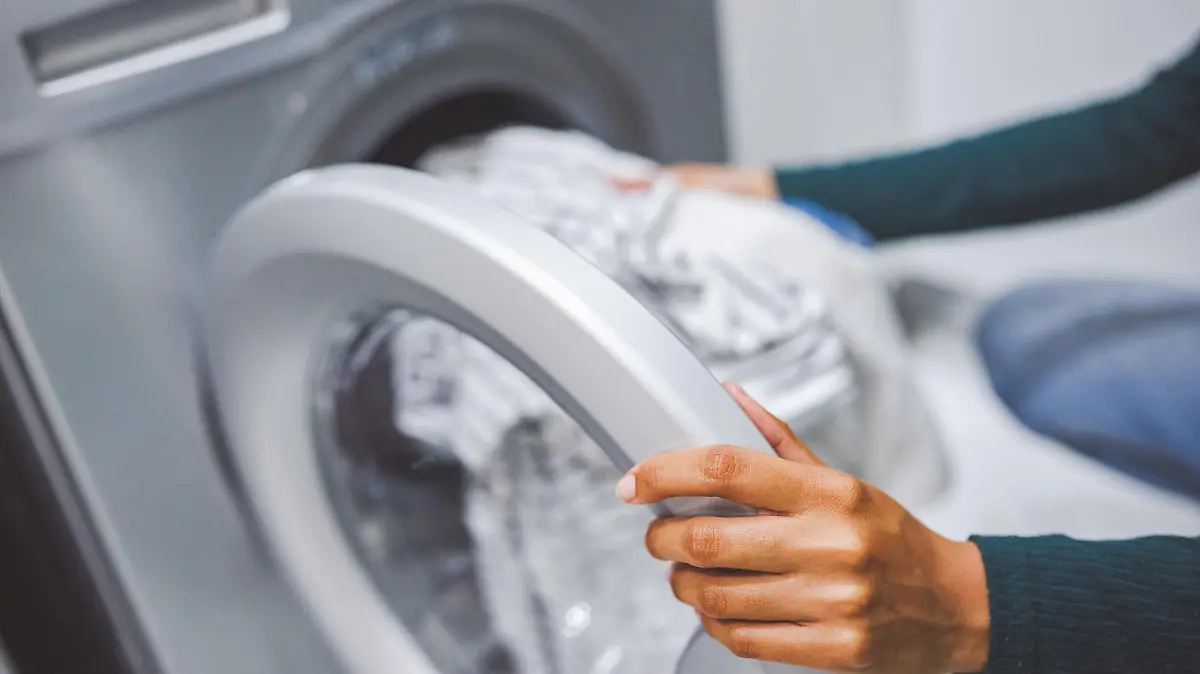 Closeup shot of an unrecognisable woman using a washing machine to do laundry at home