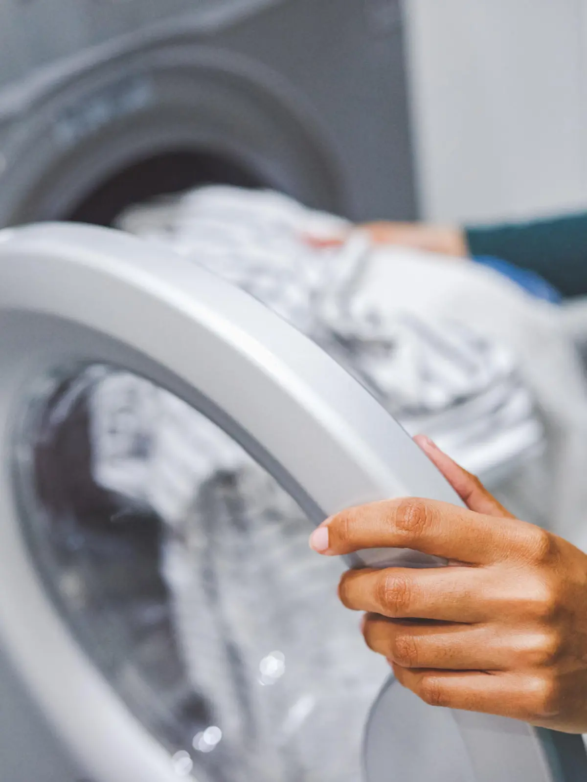 Closeup shot of an unrecognisable woman using a washing machine to do laundry at home