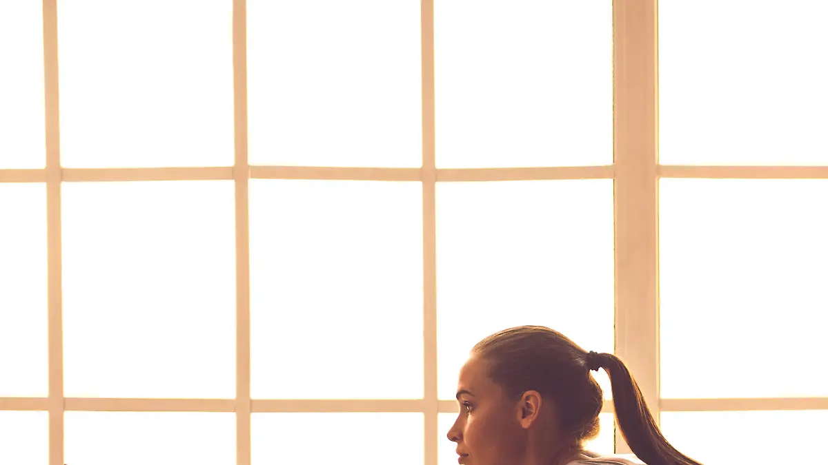 Side view of beautiful young sports lady doing yoga in fitness hall