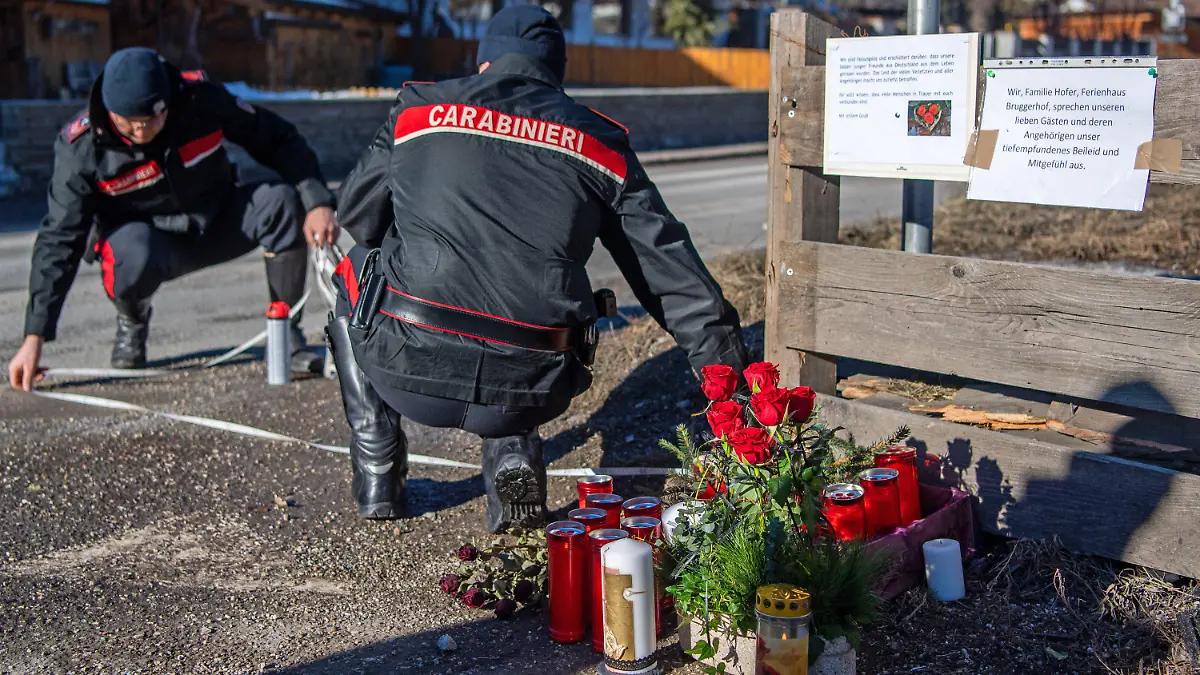 05.01.2020, Italien, Luttach: Zwei Einsatzkräfte der Carabinieri rekonstruieren den Unfallhergang. Blumen, Kerzen und Gedenkschmuck liegen am Ort des Unfalls. Ein Auto war in eine Gruppe Urlauber gefahren und hat dabei sechs Menschen getötet. Foto: Lino Mirgeler/dpa +++ dpa-Bildfunk +++