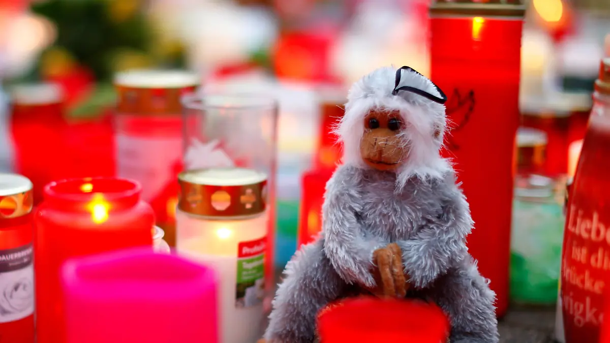 A toy monkey is seen between flowers and candles outside the zoo of Krefeld after a monkey house burned down and dozens of animals were killed by the fire in Krefeld, Germany, January 2, 2020. REUTERS/Thilo Schmuelgen     TPX IMAGES OF THE DAY