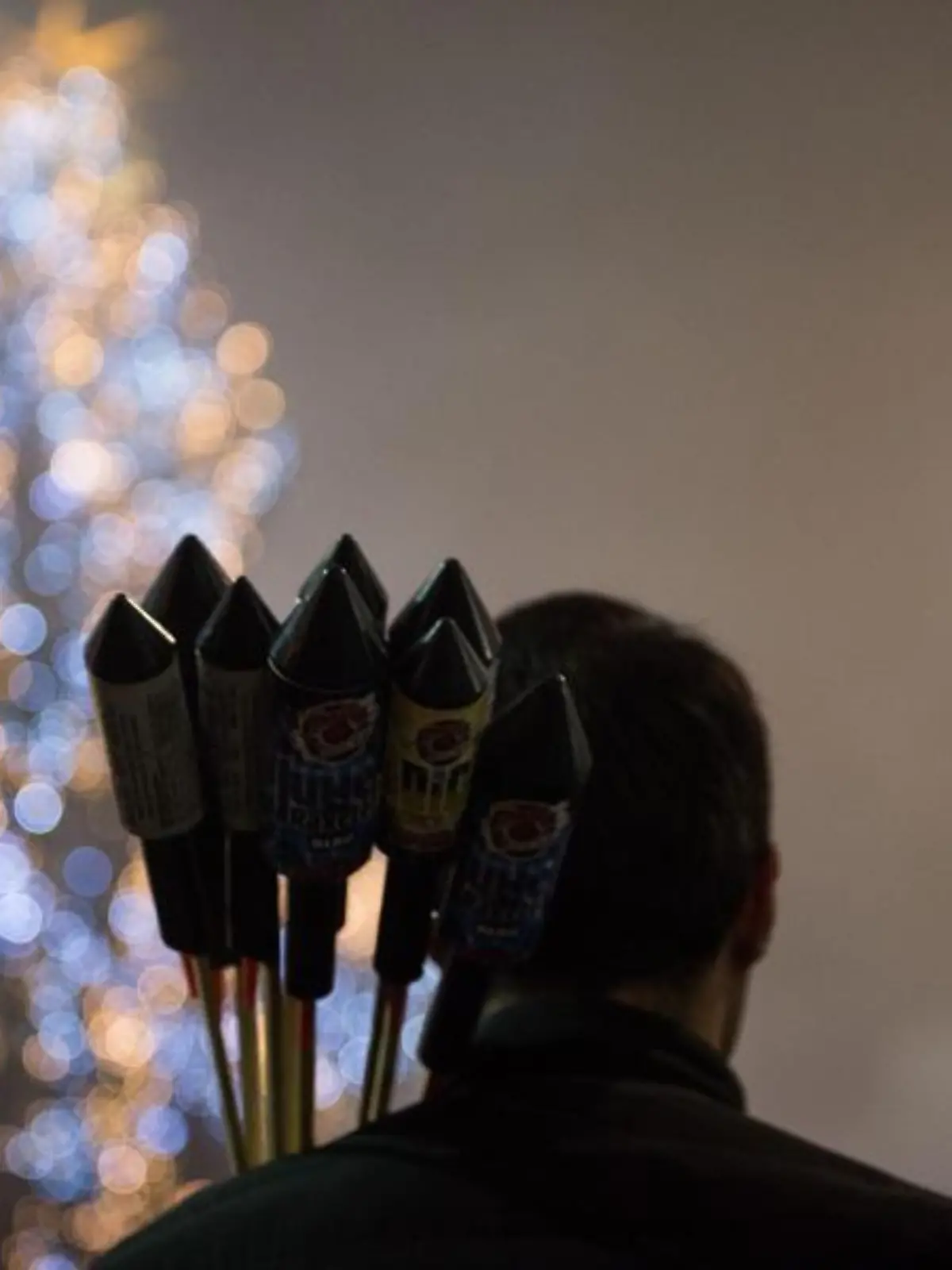 Ein Mann trägt Silvesterraketen auf der Schulter