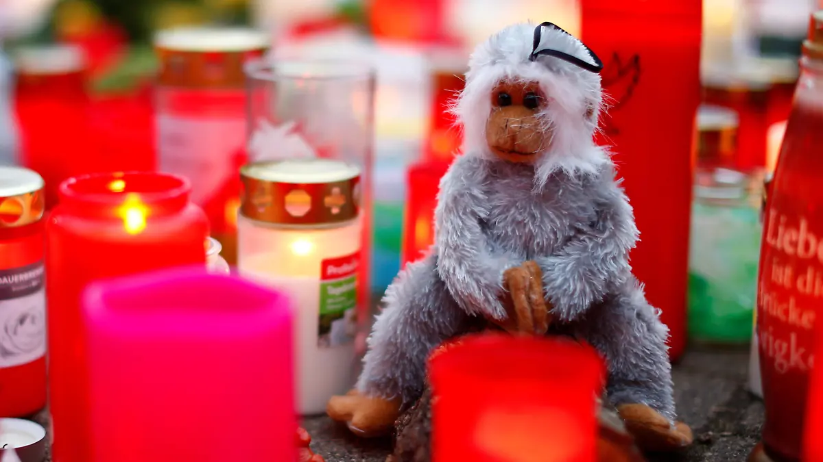 A toy monkey is seen between flowers and candles outside the zoo of Krefeld after a monkey house burned down and dozens of animals were killed by the fire in Krefeld, Germany, January 2, 2020. REUTERS/Thilo Schmuelgen