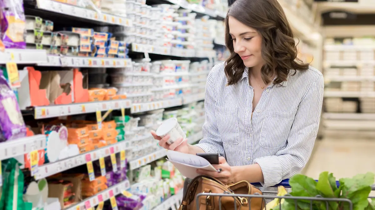 Frau liest Etikett von Joghurt im Supermarkt.