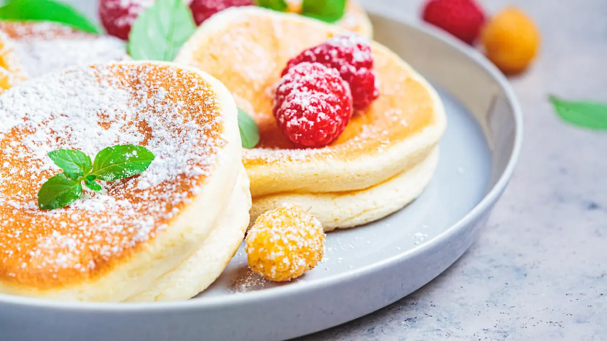 Japanese fluffy pancakes with raspberries in a gray plate, gray background. Japanese cuisine concept.