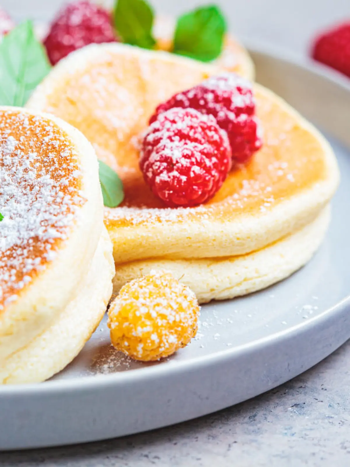 Japanese fluffy pancakes with raspberries in a gray plate, gray background. Japanese cuisine concept.