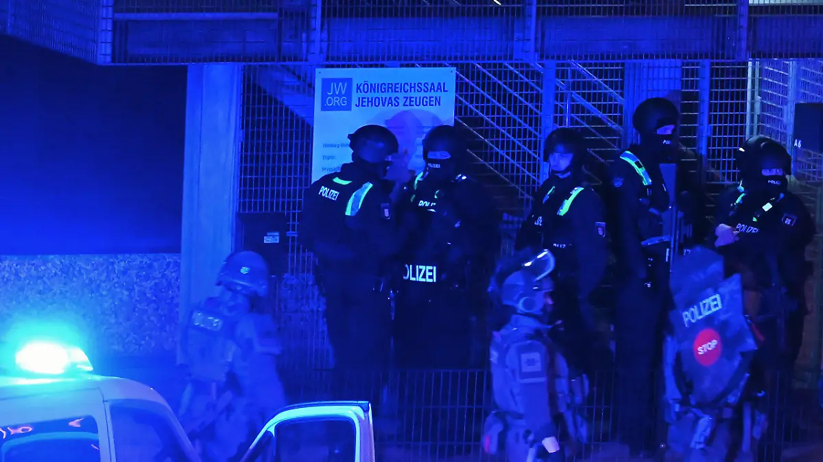 09.03.2023, Hamburg: Polizisten sind in Hamburg im Einsatz und stehen vor einem Schild mit der Aufschrift "Königreichssaal Jehovas Zeugen". Bei Schüssen in einer Hamburger Kirche sind am Donnerstagabend mehrere Menschen getötet und einige Personen verletzt worden. Foto: Jonas Walzberg/dpa +++ dpa-Bildfunk +++