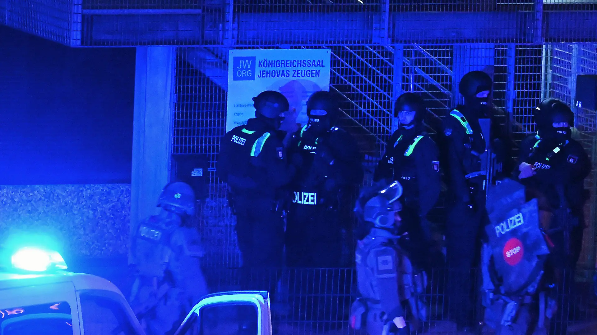 09.03.2023, Hamburg: Polizisten sind in Hamburg im Einsatz und stehen vor einem Schild mit der Aufschrift "Königreichssaal Jehovas Zeugen". Bei Schüssen in einer Hamburger Kirche sind am Donnerstagabend mehrere Menschen getötet und einige Personen verletzt worden. Foto: Jonas Walzberg/dpa +++ dpa-Bildfunk +++