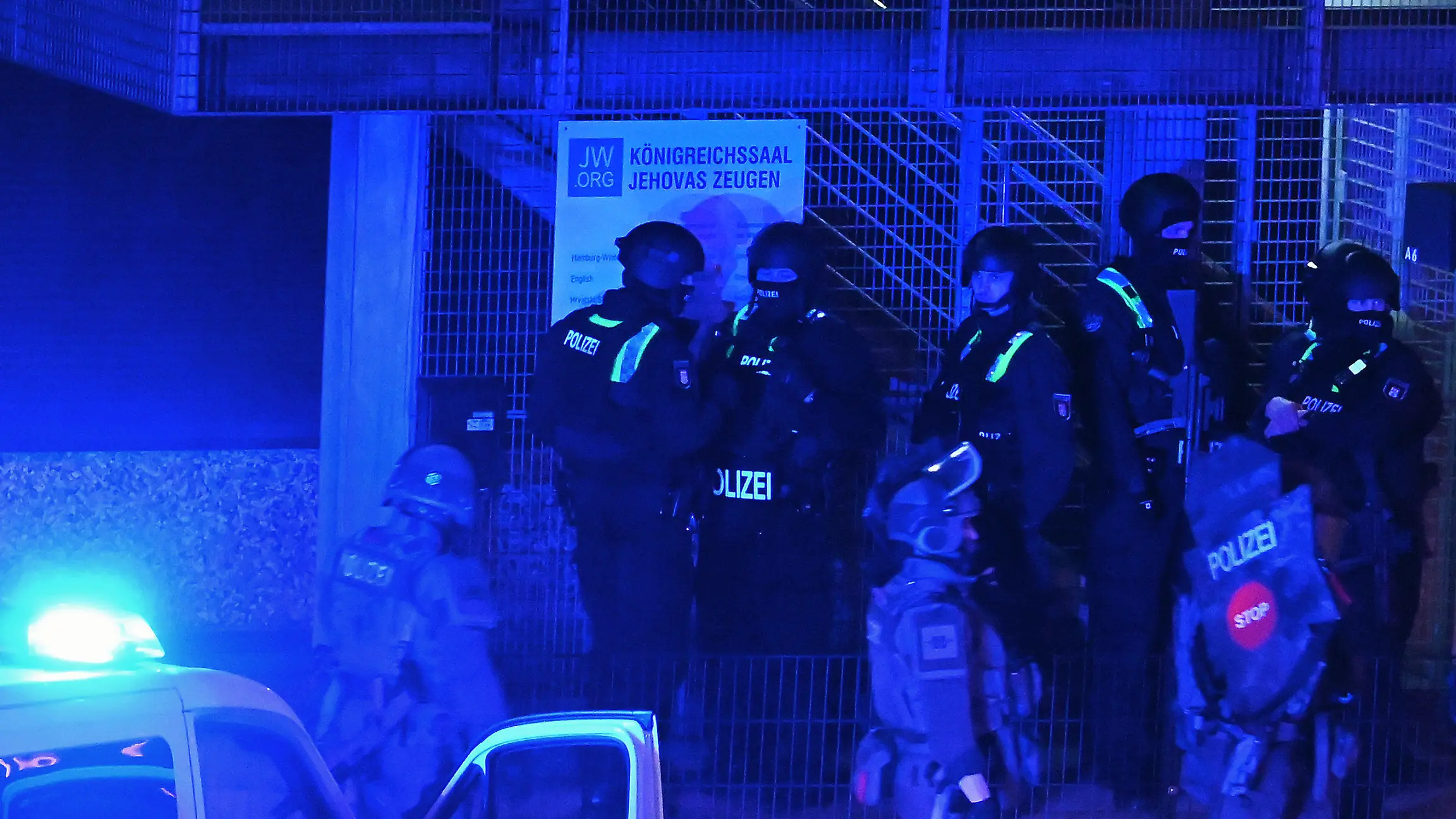 09.03.2023, Hamburg: Polizisten sind in Hamburg im Einsatz und stehen vor einem Schild mit der Aufschrift "Königreichssaal Jehovas Zeugen". Bei Schüssen in einer Hamburger Kirche sind am Donnerstagabend mehrere Menschen getötet und einige Personen verletzt worden. Foto: Jonas Walzberg/dpa +++ dpa-Bildfunk +++