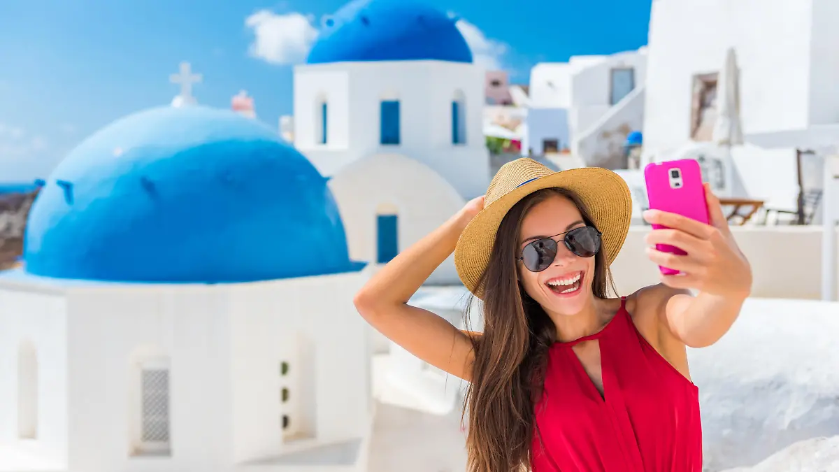 Santorini travel selfie girl taking photo having fun on European cruise holidays. Summer destination.