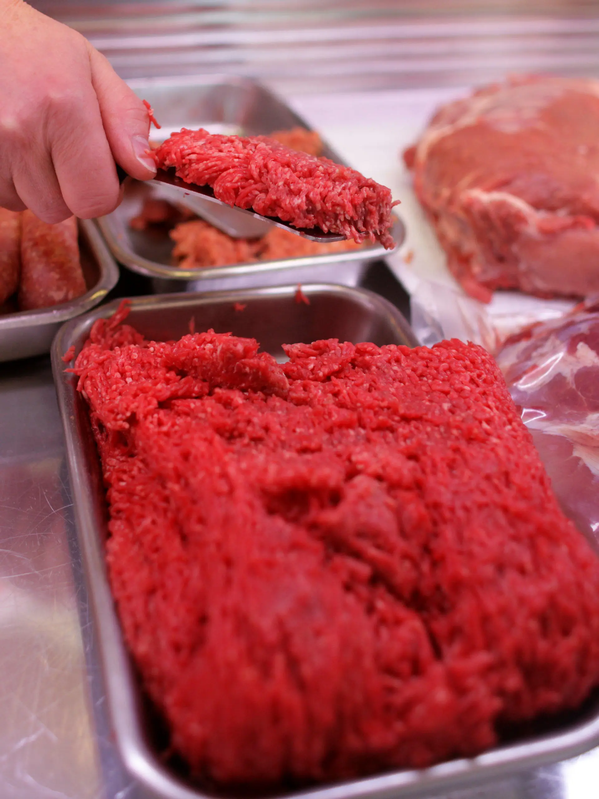 ARCHIV - ILLUSTRATION - Eine Hand entnimmt Fleisch aus einer Fleischtheke, aufgenommen am 10.01.2011 in Köln (Nordrhein-Westfalen). Biofleisch, das keines gewesen sein soll und 100 Kilogramm verdorbene Wurst: Ein Fleischer muss sich in Krefeld vor Gericht verantworten. (Zu dpa/lnw «Fleisch als Bio deklariert, Wurst verdorben: Metzger vor Gericht» vom 25.04.2017) Foto: Rolf Vennenbernd/dpa +++(c) dpa - Bildfunk+++