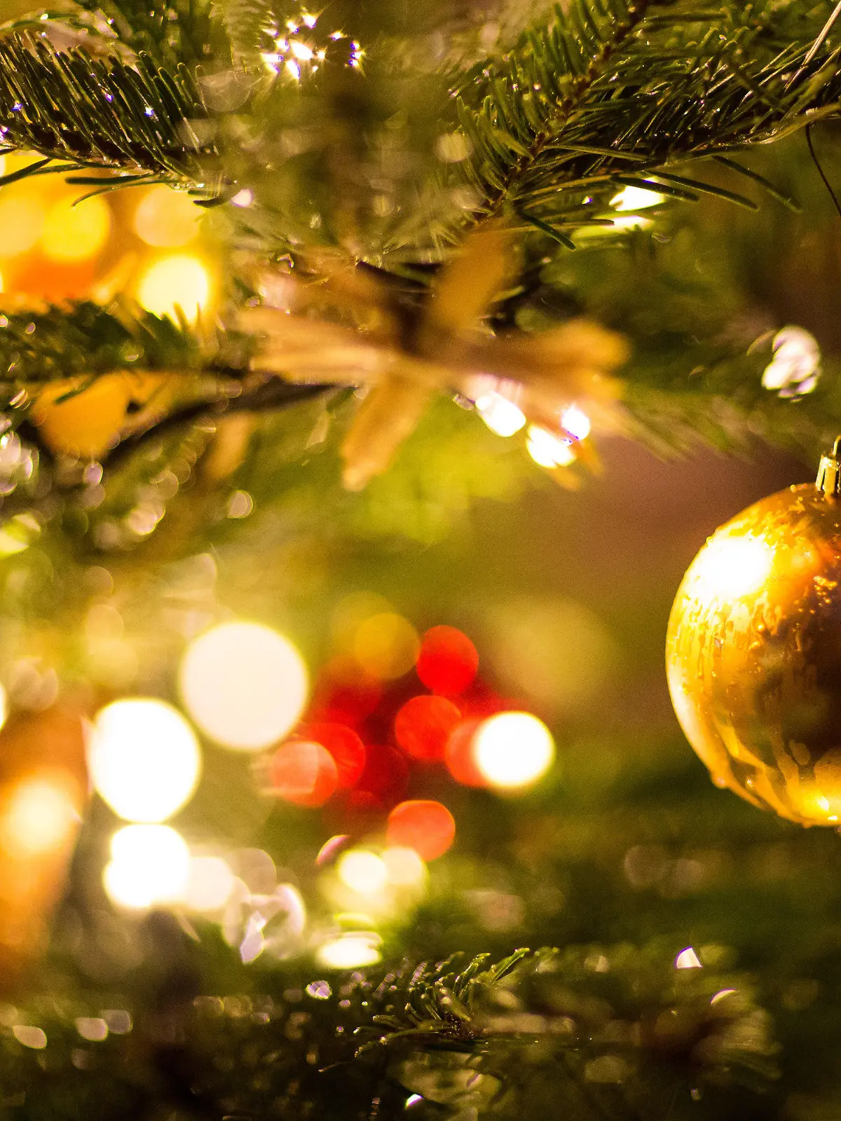 ARCHIV - 09.12.2017, Nordrhein-Westfalen, Bielefeld: Eine goldene Kugel hängt an einem Weihnachtsbaum auf dem Weihnachtsmarkt. (zu dpa: «Umfrage: Mehrheit für weniger Weihnachtsbeleuchtung wegen Klimaschutz ») Foto: Friso Gentsch/dpa +++ dpa-Bildfunk +++