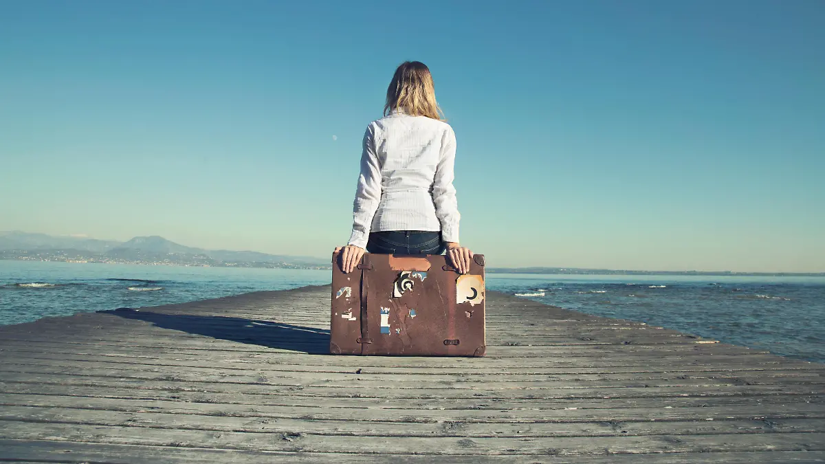 woman sitting on her suitcase waiting for the sunset in a spectacular view