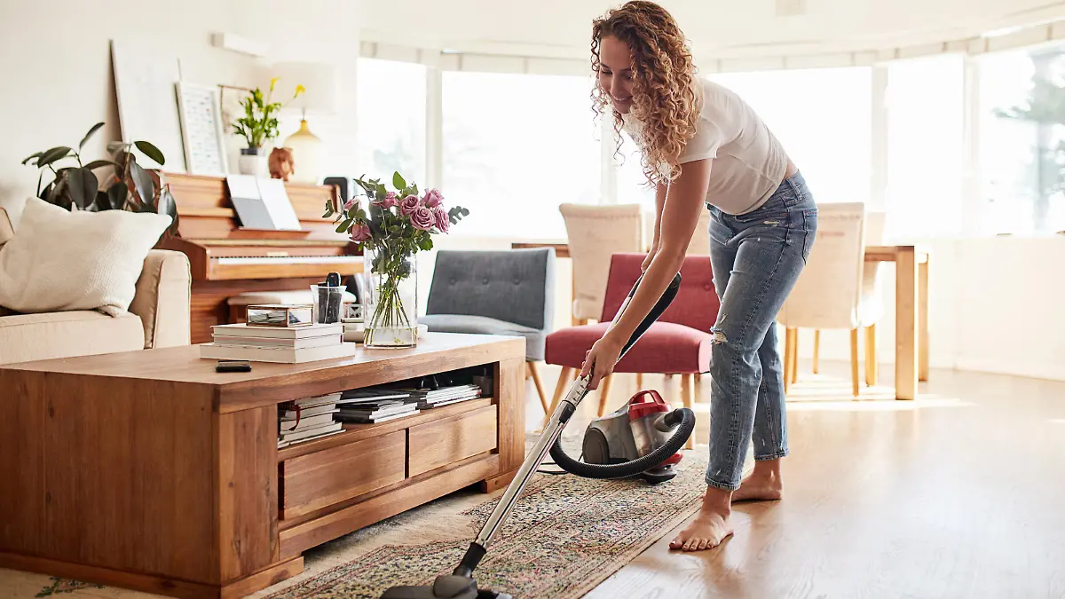 Shot of a young woman vacuuming the living room at home