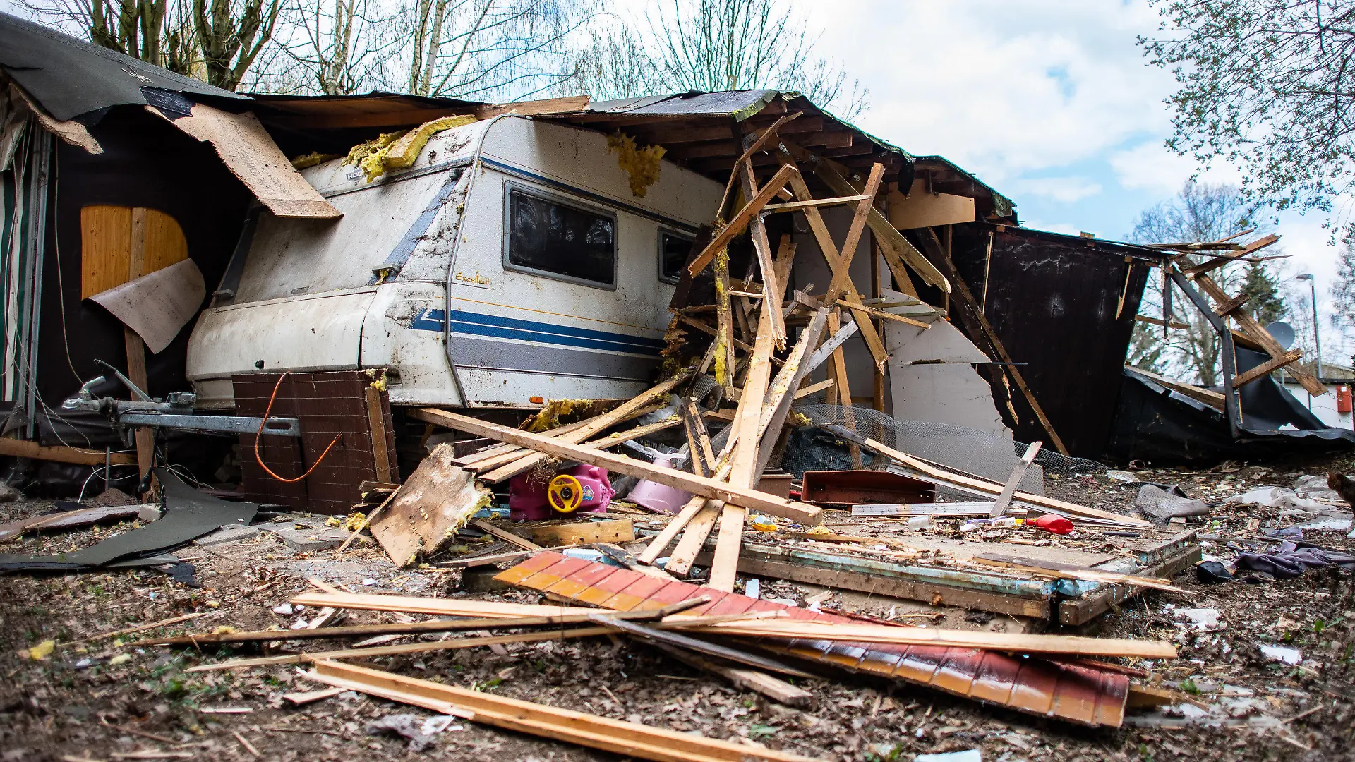 ARCHIV - 11.04.2019, Nordrhein-Westfalen, Lügde: Ein Kinderauto liegt unter dem Trümmern vor der zum Teil bereits abgerissenen Parzelle des mutmaßlichen Täters auf dem Campingplatz Eichwald im Ortsteil Elbrinxen. Der Campingplatzbetreiber lässt den Tatort abreißen, auf dem mehrere Kinder missbraucht und dabei gefilmt wurden. Im Fall des massenhaften Kindesmissbrauchs in Lügde in Nordrhein-Westfalen hat das Landgericht Detmold die Anklageschrift gegen zwei der drei Beschuldigten erhalten. Das bestätigte ein Gerichtssprecher am Dienstag. Foto: Guido Kirchner/dpa +++ dpa-Bildfunk +++