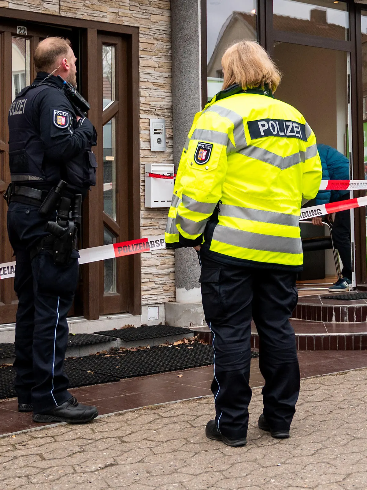 09.03.2023, Schleswig-Holstein, Aumühle: Polizisten stehen vor einem Wohn- und Geschäftshaus. Eine 41-jährige Frau ist dort tot gefunden worden, die Ermittler gehen von einem Gewaltverbrechen aus. (zu dpa: «41-Jährige in Aumühle tot gefunden - Ehemann unter Tatverdacht») Foto: Daniel Bockwoldt/dpa +++ dpa-Bildfunk +++