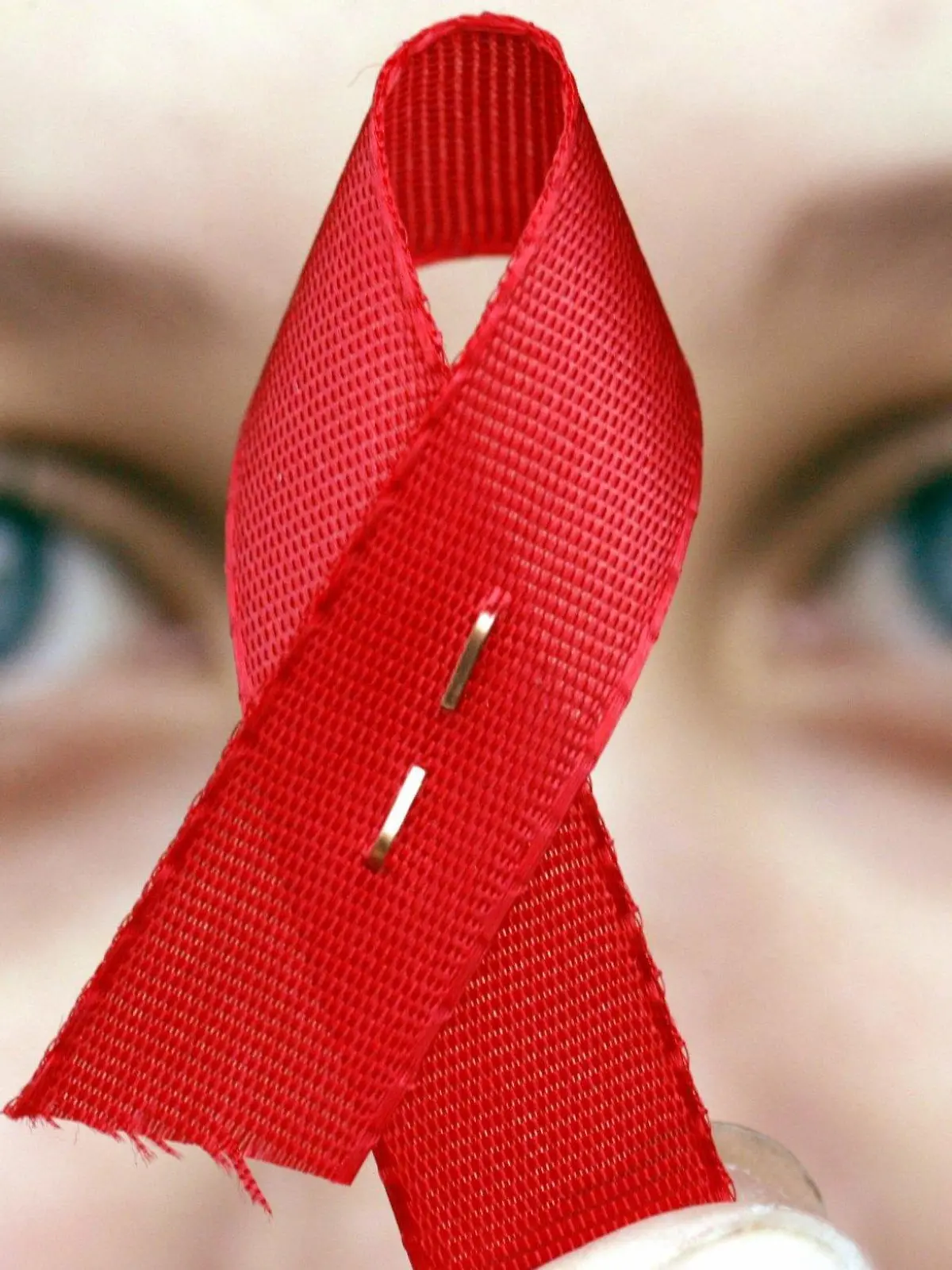 Eine Schülerin des Gymnasiums am Deutenberg hält in Villingen-Schwenningen (Schwarzwald-Baar-Kreis) am Welt-AIDS-Tag eine rote Schleife in den Händen (Archivfoto vom 01.12.2003). Rund 5000 Menschen in Baden-Württemberg leben mit dem tödlichen Aidsvirus - und es werden immer mehr. Im ersten Halbjahr 2005 haben sich rund 130 Menschen neu mit dem HI-Virus infiziert und damit etwa so viele wie im Vorjahreszeitraum. Die Grünen im Landtag fordern, die Anstrengungen bei der Prävention wieder zu verstärken. Sozialminister Andreas Renner (CDU) sicherte trotz knapper Finanzen und Kürzungen bei den Zuschüssen für die Aids-Hilfe weitere Fördermittel zu. Foto: Patrick Seeger dpa/lsw (zu dpa/lsw-Thema des Tages vom 22.11.2005) +++(c) dpa - Bildfunk+++