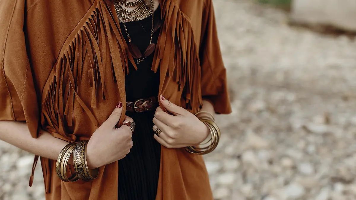 stylish hipster boho traveler woman look. gypsy girl in fringe jacket with feather bronze accessory. wanderlust summer travel. atmospheric moment. space for text.