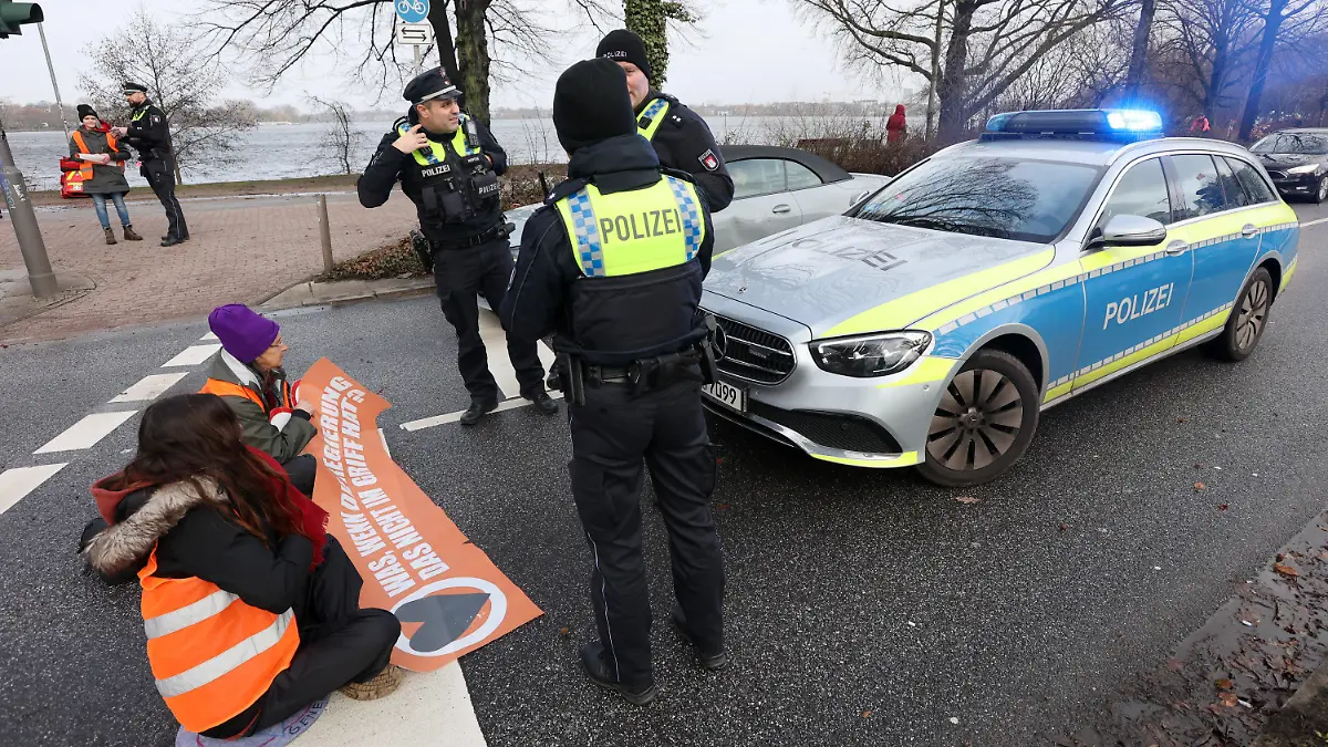 03.02.2023, Hamburg: Aktivisten der Klimaschutzbewegung Letzte Generation haben sich auf der Fahrbahn an der Zufahrt zur Kennedybrücke festgeklebt und wollen damit auf die Einhaltung der Klimaziele aufmerksam machen. Foto: Bodo Marks/dpa +++ dpa-Bildfunk +++