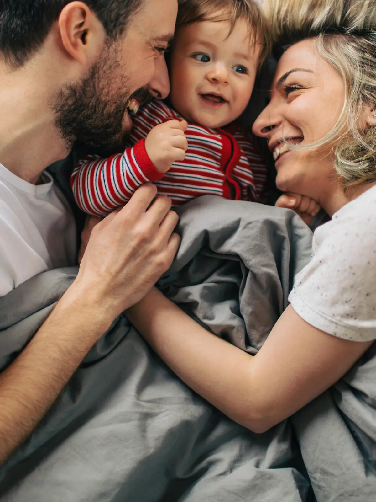 Familie kuschelt im Bett