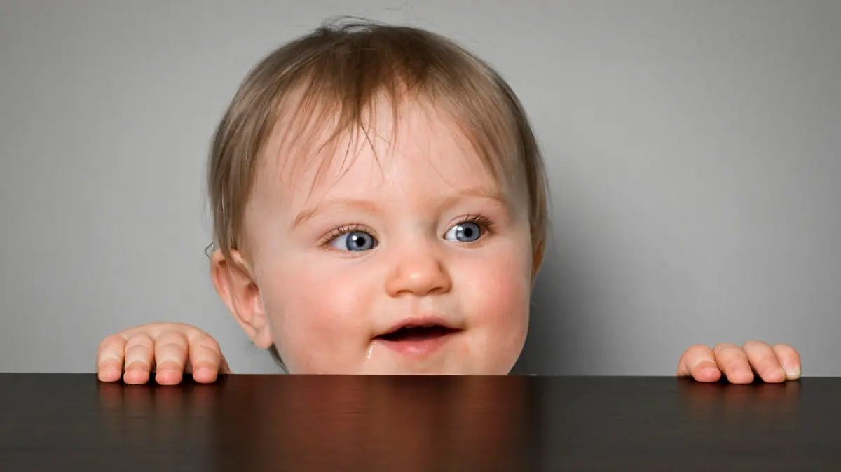 Baby schaut fröhlich über Tisch