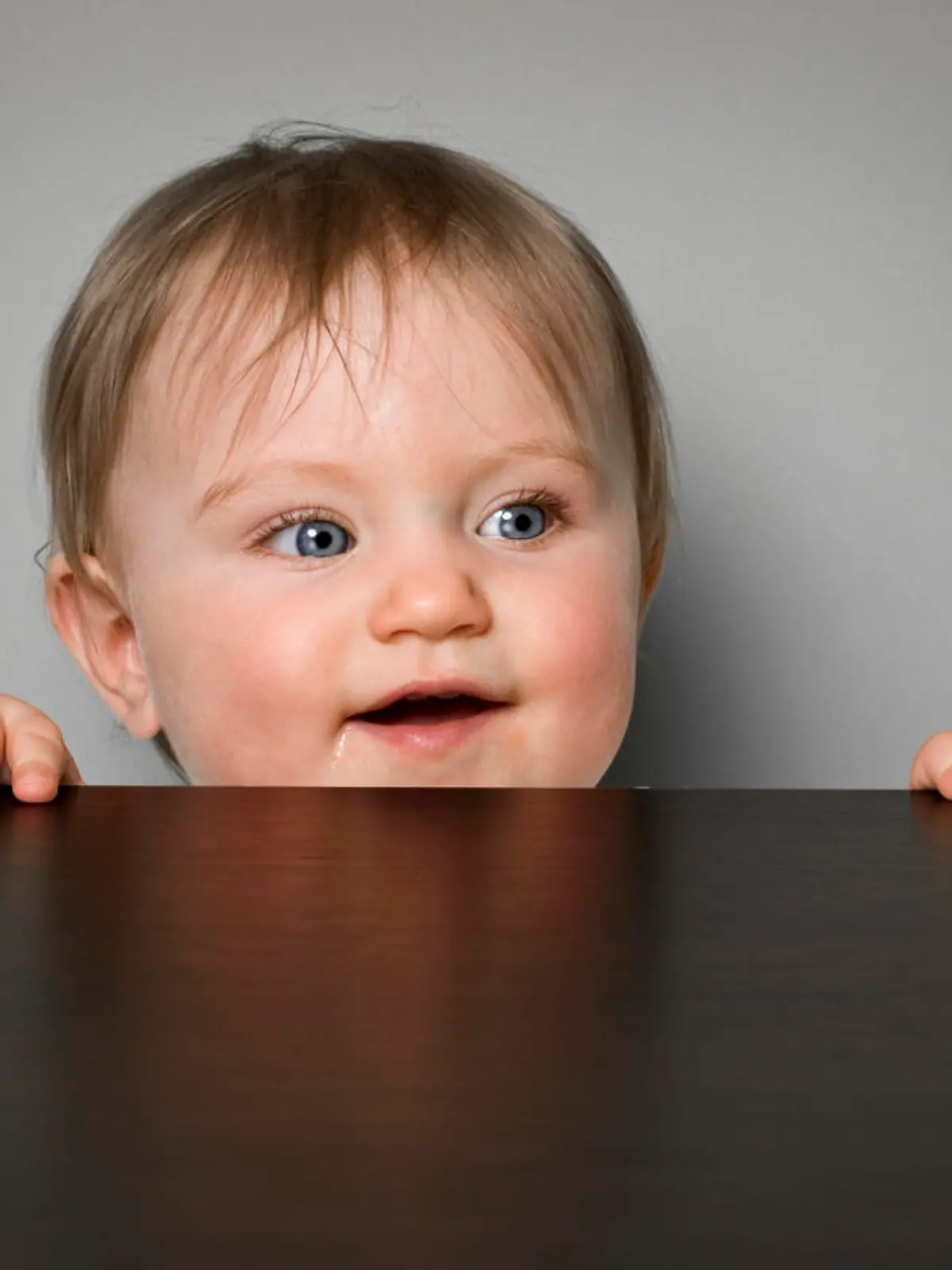 Baby schaut fröhlich über Tisch