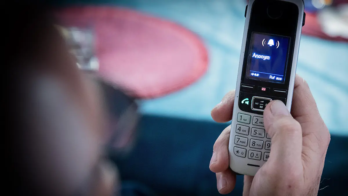 Bamberg, Deutschland 26. Dezember 2022: Themenbilder - Symbolbilder - Telefonbetrug - 2022 Ein älterer Menschen sitzt in seiner Wohnung und hält ein Telefon, Mobilteil in der Hand. Auf dem Display steht keine Rufnummer sondern Anonym. Viele Senioren und Seniorinnen werden Opfer von Telefonbetrug, darunter fällt auch der Enkeltrick oder auch der Schockanruf Bei diesen Anrufen werden teilweise auch Telefonnummern manipuliert, welche dann auf dem Mobilteil angezeigt werden.