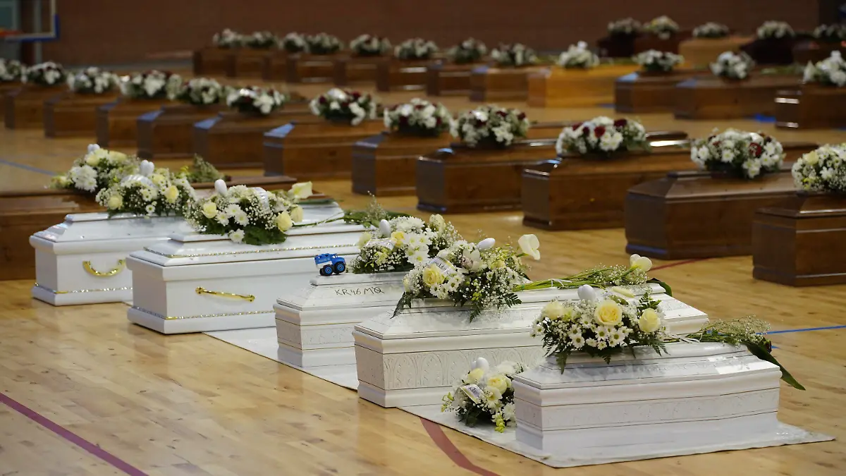 28.02.2023, Italien, Crotone: Die Särge der Opfer eines Bootsunglücks stehen mit Blumen bedeckt in der örtlichen Sporthalle. Bei einem Bootsunglück vor der italienischen Küste sind über 60 Migranten gestorben und Dutzende werden vermisst. Foto: Antonino D'Urso/LaPresse/AP/dpa +++ dpa-Bildfunk +++