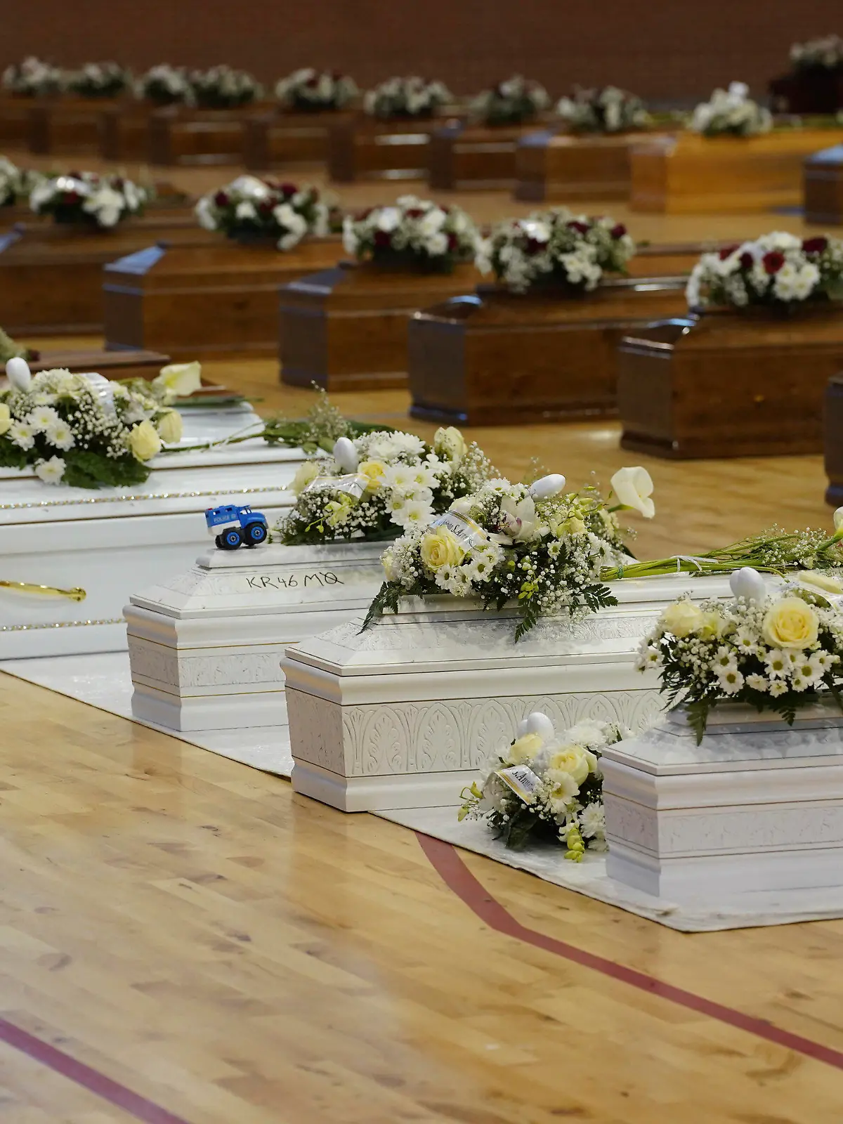28.02.2023, Italien, Crotone: Die Särge der Opfer eines Bootsunglücks stehen mit Blumen bedeckt in der örtlichen Sporthalle. Bei einem Bootsunglück vor der italienischen Küste sind über 60 Migranten gestorben und Dutzende werden vermisst. Foto: Antonino D'Urso/LaPresse/AP/dpa +++ dpa-Bildfunk +++