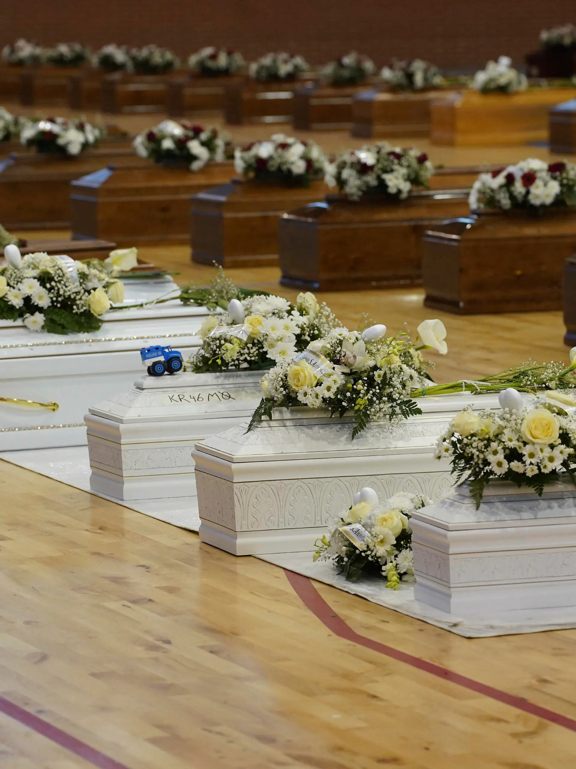 28.02.2023, Italien, Crotone: Die Särge der Opfer eines Bootsunglücks stehen mit Blumen bedeckt in der örtlichen Sporthalle. Bei einem Bootsunglück vor der italienischen Küste sind über 60 Migranten gestorben und Dutzende werden vermisst. Foto: Antonino D'Urso/LaPresse/AP/dpa +++ dpa-Bildfunk +++