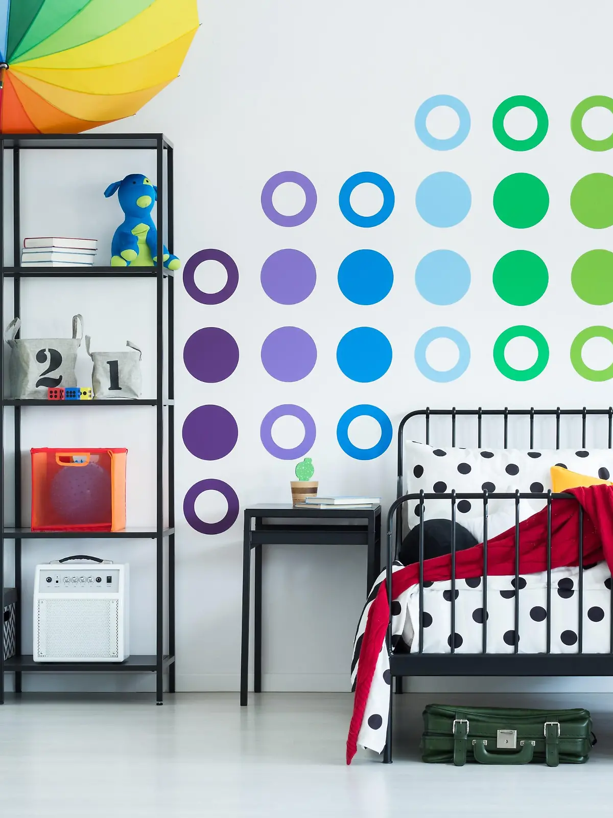 Colorful wall sticker in child's room with yellow clock on black stool and pouf on the floor
