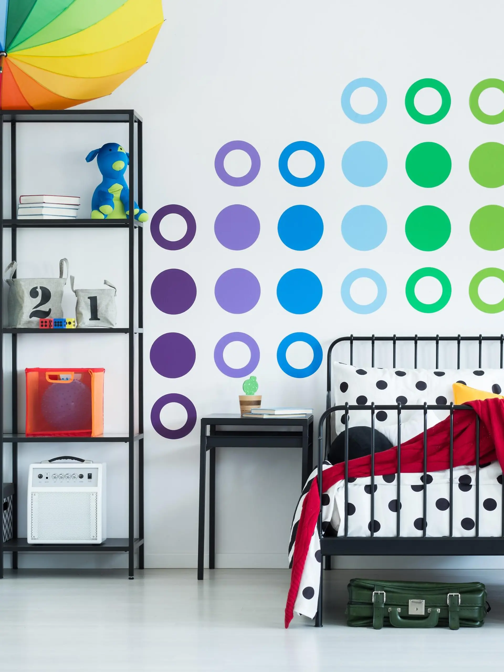 Colorful wall sticker in child's room with yellow clock on black stool and pouf on the floor