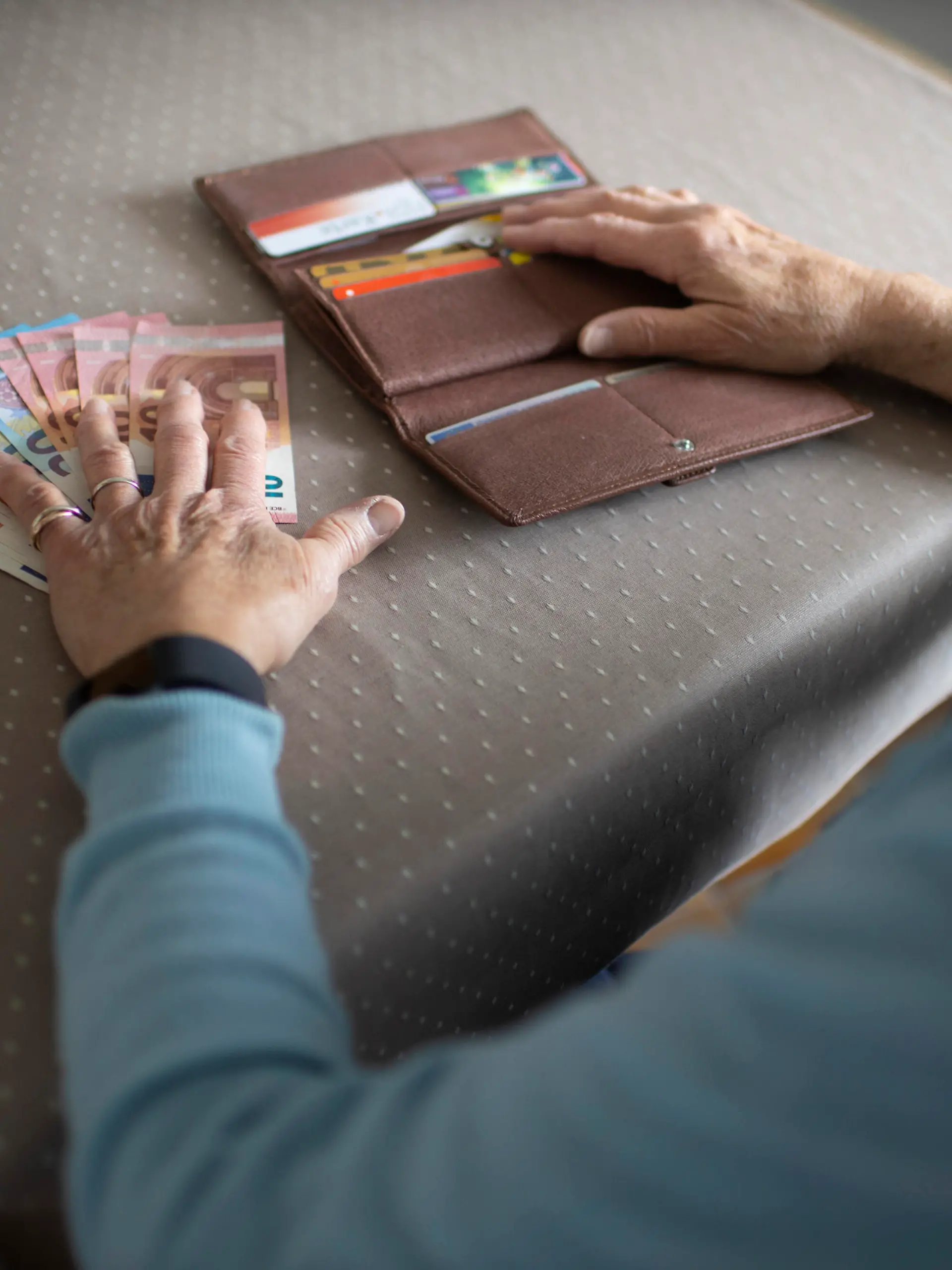 Rentnerin mit Bargeld am Kuechentisch.