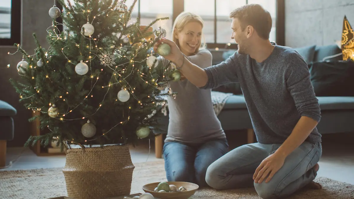 Schwangere Frau schmückt Weihnachtsbaum