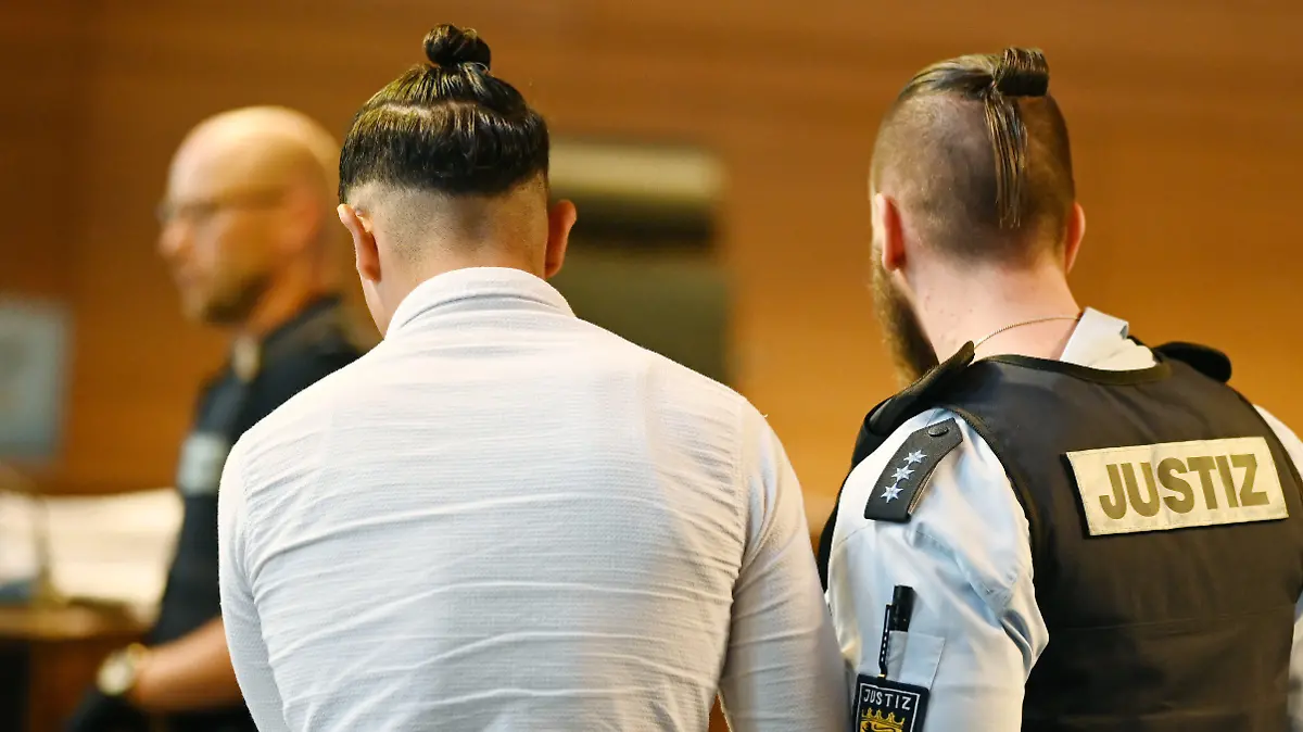 18.05.2019, Baden-Württemberg, Freiburg: Einer von elf Angeklagten wird vor dem Prozessbeginn von einem Justizbeamten in einen Gerichtssaal im Landgericht gebracht. Elf Männer sollen laut Anklage Mitte Oktober 2018 eine 18-Jährige nachts in einem Gebüsch vor einer Diskothek vergewaltigt haben. Foto: Patrick Seeger/dpa +++ dpa-Bildfunk +++